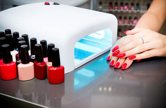 Manicure set in a beauty salon. Beautiful female hands. Machine for drying naroshchennyh nail UV lamp.